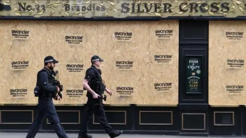 EPA Two police officers walk past a boarded-up pub