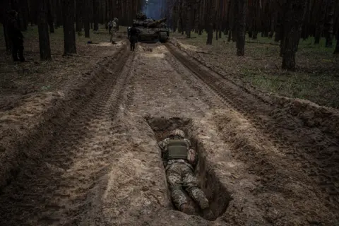 DIMITAR DILKOFF/AFP A Ukrainian serviceman lies in a trench during a military exercise in the Kharkiv region of Ukraine