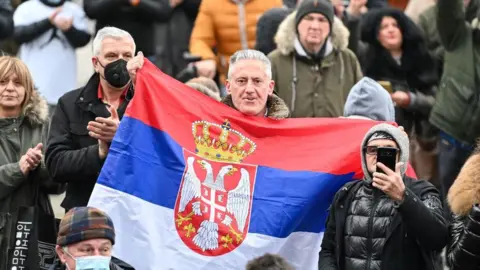 Getty Images A man holds up a Serbian flag during a pro-Djokovic rally in Belgrade