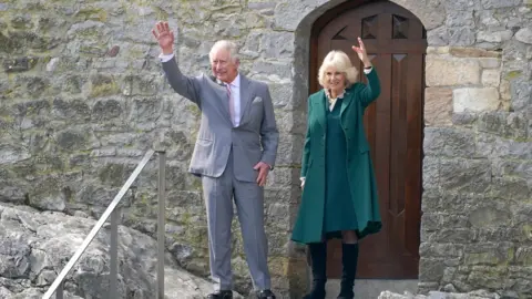 PA Media The Prince of Wales and the Duchess of Cornwall wave as they leave Cahir Castle, during a visit to Cahir in County Tipperary