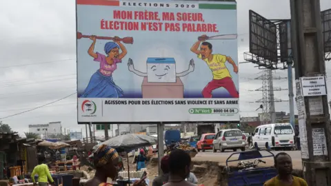AFP People walk past a billboard in Yopougon, a popular district of Abidjan, which promotes peaceful elections in Ivory Coast