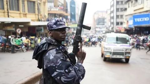 AFP A police officer with a weapon to shoot tear gas canisters in Kampala, Uganda - Wednesday 11 July 2018