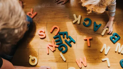 Getty Images A parent and child playing with plastic letters