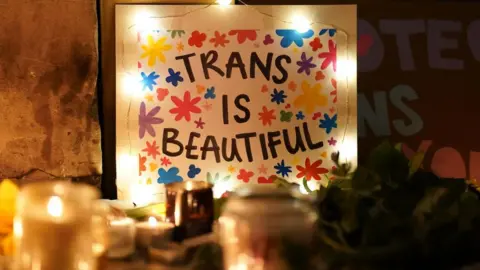 PA Media Candles with a sign outside the Department of Education in London as members of the public attend a candle-lit vigil in memory of transgender teenager Brianna Ghey, who was fatally stabbed in a park on Saturday.