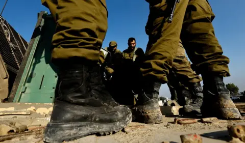 Reuters Israeli soldiers standing, Israel: Israeli soldiers prepare on the Israeli side of the border with Gaza in southern Israel, December 18, 2023