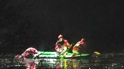 PA Media Emergency workers on board a boat on the lake in Babs Mill Park