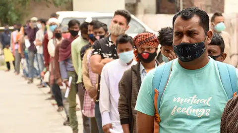 EPA People wait in queue for their turn for COVID-19 testing at a test centre in Jammu, the winter capital of Kashmir, India, 20 April 2021.