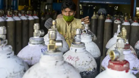 Getty Images Worker arranges oxygen cylinders for transport to hospital in Hyderabad, India (23 April)