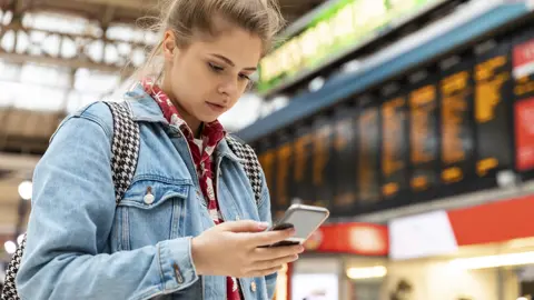 Getty Images Person on phone at train station