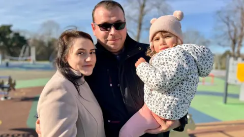 Nikki Fox/BBC Emi Iancu, 31, with his wife Laura and daughter Ayla