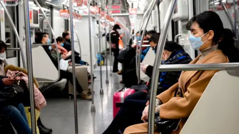 Getty Images People wearing protective face masks commute on a train in Shanghai.