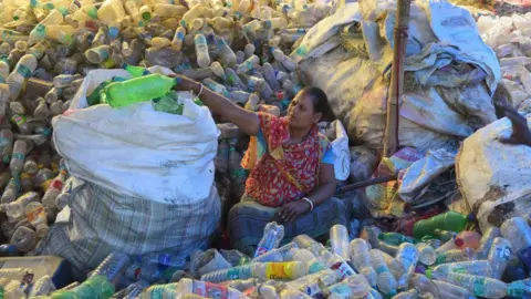 Getty Images SOUTH 24 PARGANAS, WEST BENGAL, INDIA - 2022/07/30: A woman seen sorting plastic bottles at a workshop before sending them for recycling.