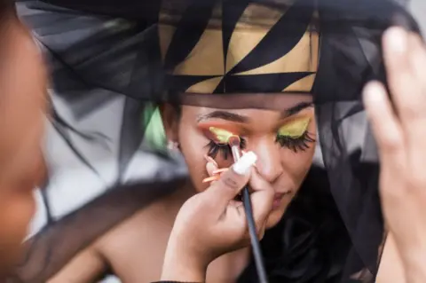 AFP A model gets her make up done during a fashion show at the 2022 editon of the Durban July horse race in Durban on July 2, 2022. - The Durban July race is the biggest horse racing event on the African continent and a high social event where South African celebrities dress up and watch the race. The race attracts close to 100,000 spectators.