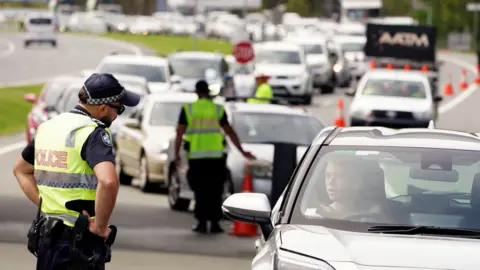 EPA Police checking the border entry requirements of car passengers waiting to cross into Queensland from New South Wales