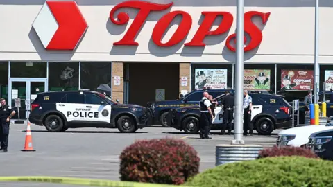 AFP Police cars and tape outside a Tops supermarket in Buffalo, New York where the shooting took place