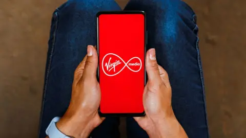 Getty Images A stock image of a phone displaying the Virgin Media logo