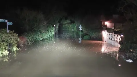 Northamptonshire Fire and Rescue Water seen on a narrow road with trees and bushes either side