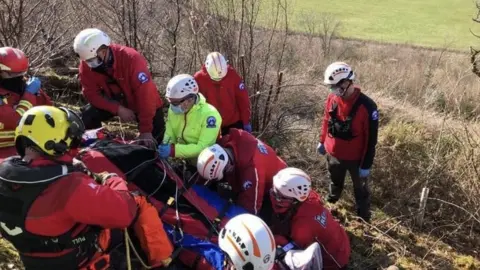 Brecon Mountain Rescue Team Paraglider being treated before being flown to hospital after crashing on hillside in Powys