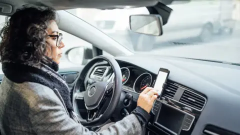 Getty Images woman in car setting phone