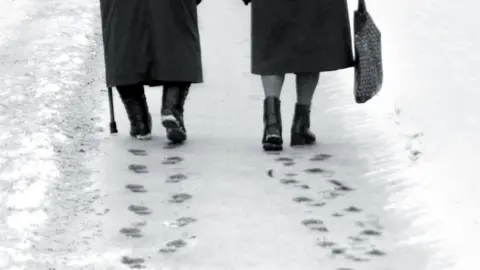 Vladimirs Prusakovs/Getty Elderly pair walking on snow