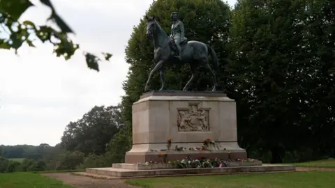 Statue on a plinth of the Queen riding a horse