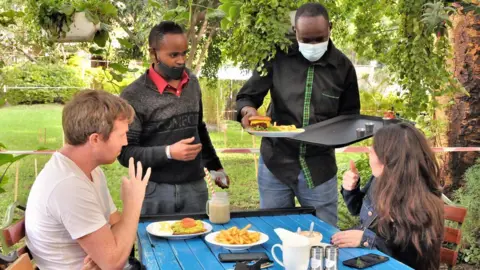 Peter Njoroge/BBC Waiters serving a table