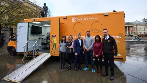 City Hall Sadiq Khan and Debt Free Advice staff in front of bus