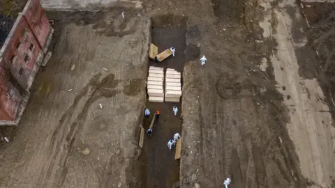 Reuters Drone pictures show bodies being buried in a wide trench on New York's Hart Island