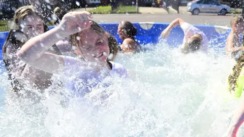 Pacemaker Children playing in paddling pool in Belfast street