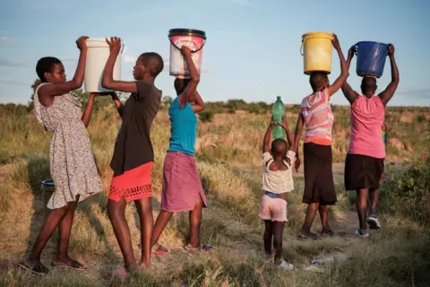 KB MPOFU / REUTERS People carry water in buckets
