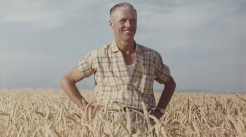 Dr Norman Borlaug standing in a wheat field