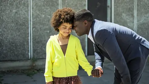 Netflix Amelie Dokubo and David Oyelowo touch heads while standing outside during a tender moment in The After