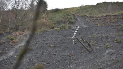 Matthew Gauvain A telegraph pole on its side in a landslide