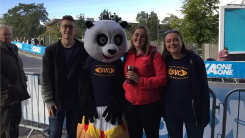 Three students and a person dressed as a Panda