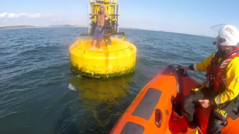 RNLI Porthcawl RNLI boat approaches stranded kayaker on a buoy off Porthcawl, Bridgend