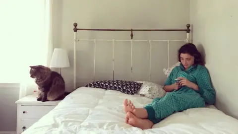 Getty Images Teenager sits up on bed looking at phone