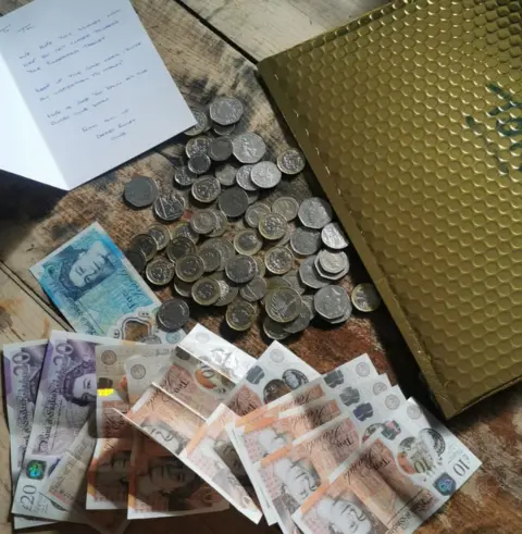 Tom Wilson Notes and coins alongside a golden envelope and card for Tom