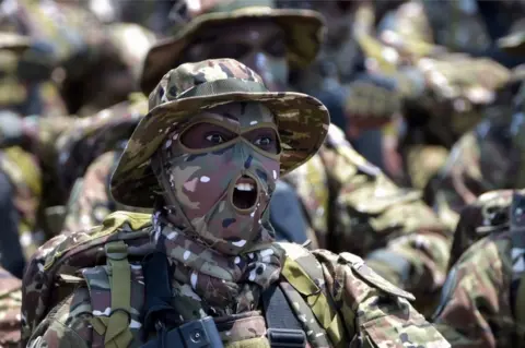 AFP A member of the Ivorian Special Forces chants as he marches at a parade in the capital, Abidjan.