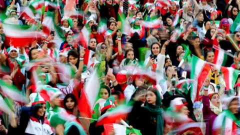 AFP Iranian women cheer during the World Cup Qatar 2022 Group C qualification football match between Iran and Cambodia at the Azadi stadium in the capital Tehran on 10 October, 2019.