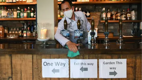 EPA A bar man wearing a mask at a pub in Chessington