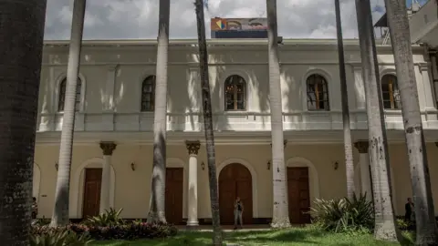 Alejandro Cegarra A view of the National Assembly building with a poster of Hugo Chávez's eyes