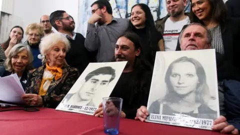 Reuters Mr Darroux, his uncle Roberto and Estela de Carlotto, president of Grandmothers of Plaza de Mayo, hold up photos of Mr Darroux's parents