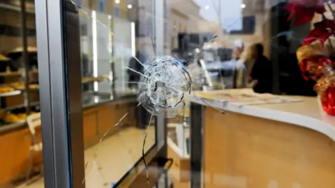 AFP A bullet hole in a shop window as police investigate the shooting of foreign nationals at Macerata, 3 February 2018