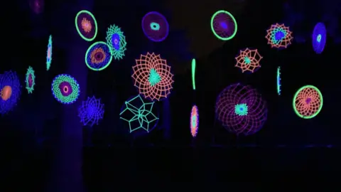 BBC Multi-coloured glowing wool tied together in patterns stands out from the darkness.