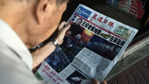 Reuters Man reading Thai newspaper