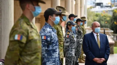 EPA State Police Minister David Elliott stands in front of Defence soldiers at a press briefing this week