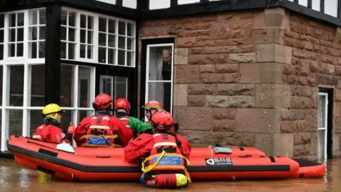 PA Media Mountain Rescue team members attempt to rescue a man from his house that is surrounded by heavy flood water in Monmouth, in the aftermath of Storm Dennis