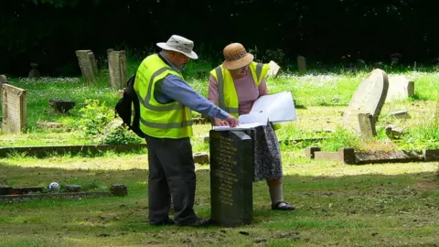 Friends of Foster Hill Cemetery Two people standing by a gravestone