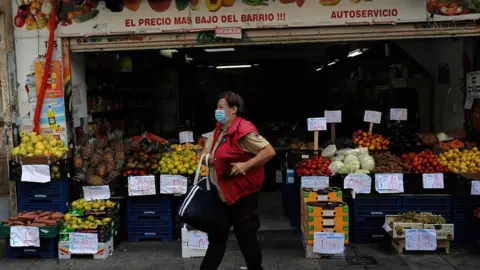 Getty Images Masked shopper leaves a grocery store in Madrid on 18 September 2020