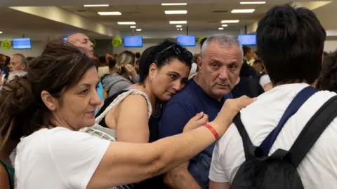 Reuters Holidaymakers queue at airport after being evacuated from Rhodes
